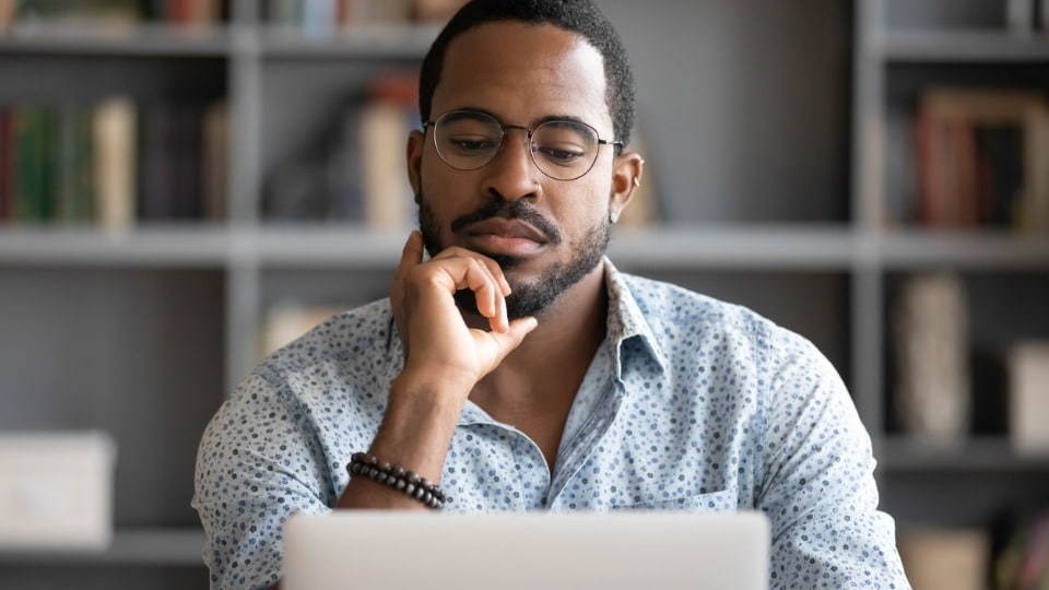 man staring at computer in serious thought